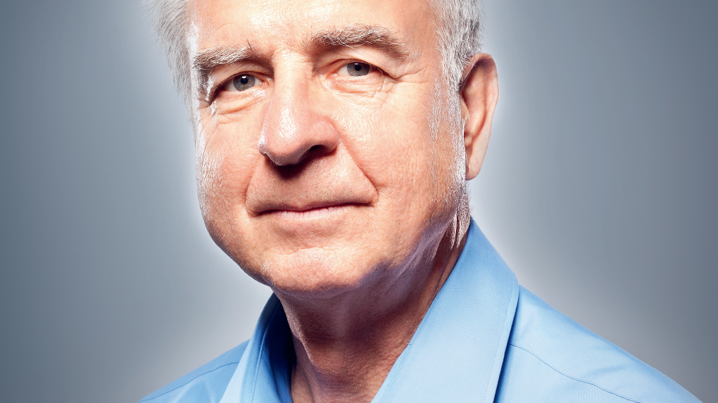 Porträt eines älteren Mannes mit grauem Haar, der in einem hellblauen Hemd freundlich in die Kamera schaut.