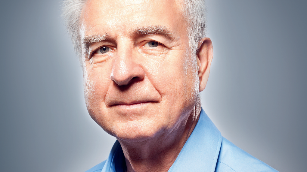 Porträt eines älteren Mannes mit grauem Haar, der in einem hellblauen Hemd freundlich in die Kamera schaut.